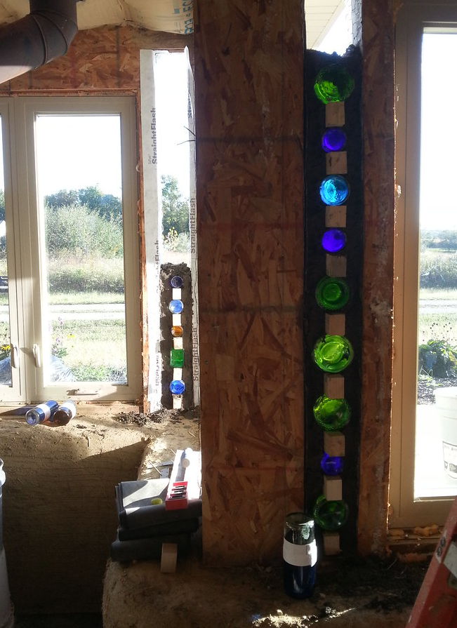 Glass bottle wall glowing like stained glass inside the Earthship at Peaceful Acres Lavender Farm